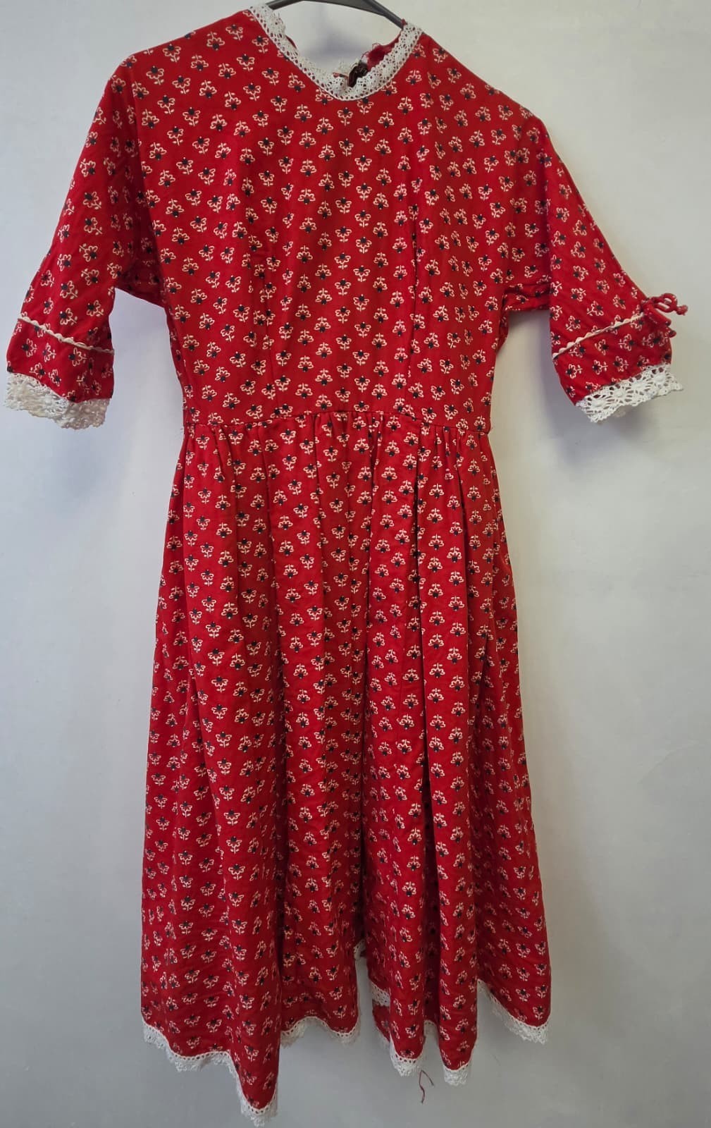 This vintage 1950s red dress features a Dutch heart print and delicate white lac